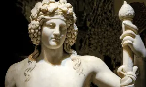 Sculpture de marbre d'une déesse du vin, couronnée de grappes de raisin, tenant un bâton orné.