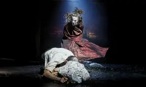 Sur scène, une figure tourmentée, peut-être Clytemnestre, domine deux hommes à terre. La tragédie des Atrides se joue dans l'ombre.