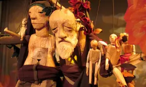 Marionnettes en bois sculpté, évoquant Philémon et Baucis, avec des visages expressifs et des corps articulés, suspendues par des fils.