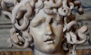 Sculpture de la gorgone mythologie, son visage figé dans une expression de douleur, ses cheveux remplacés par des serpents enroulés.