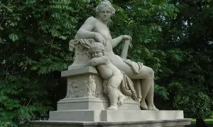Statue de Hercule et Mégara, une femme assise et un enfant s'appuyant sur elle, dans un parc verdoyant.