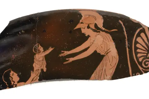 Fragment de poterie grecque montrant une femme casquée, peut-être Athéna, tendant les bras vers un enfant. Une autre figure est agenouillée. L'image évoque la protection maternelle, comme celle d'une mère pour ses fils d'Athéna.