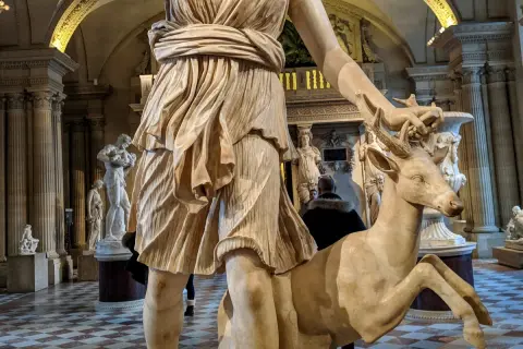 Statue d'Artémis caressant un cerf, un artémis animal emblématique de la déesse de la chasse, dans un musée.