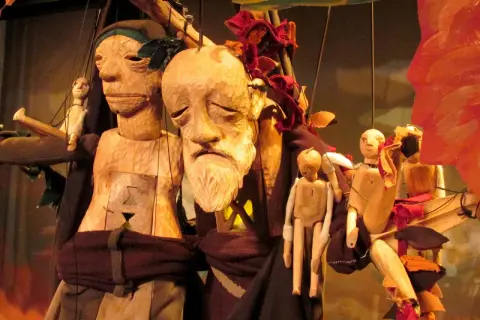 Marionnettes en bois sculpté, évoquant Philémon et Baucis, avec des visages expressifs et des corps articulés, suspendues par des fils.