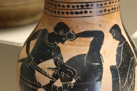 Vase antique représentant Thésée combattant le Minotaure. Un homme, qui est Thésée, lutte contre une créature mi-homme mi-taureau.