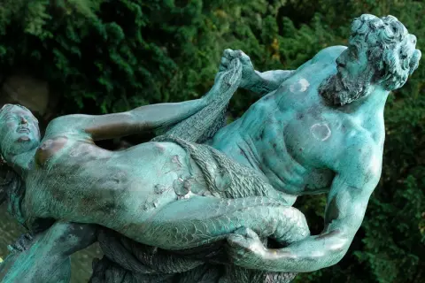 Sculpture de bronze patiné représentant un homme musclé, peut-être un attribut de Poséidon, luttant avec une femme.