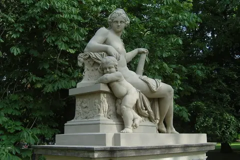 Statue de Hercule et Mégara, une femme assise et un enfant s'appuyant sur elle, dans un parc verdoyant.