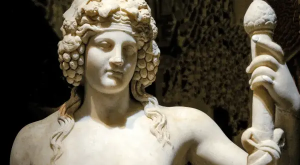 Sculpture de marbre d'une déesse du vin, couronnée de grappes de raisin, tenant un bâton orné.