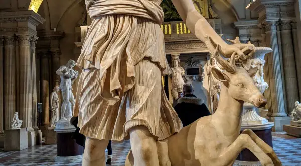Statue d'Artémis caressant un cerf, un artémis animal emblématique de la déesse de la chasse, dans un musée.