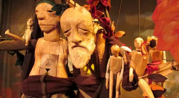 Marionnettes en bois sculpté, évoquant Philémon et Baucis, avec des visages expressifs et des corps articulés, suspendues par des fils.