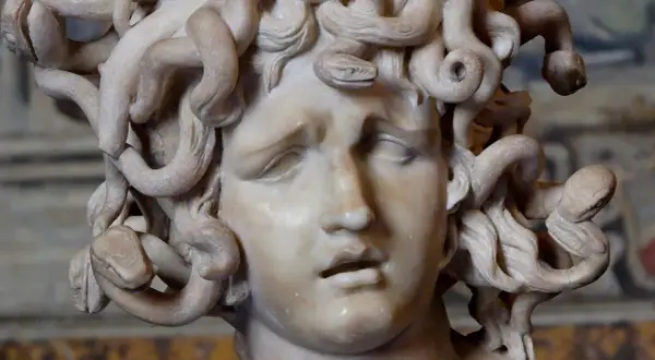 Sculpture de la gorgone mythologie, son visage figé dans une expression de douleur, ses cheveux remplacés par des serpents enroulés.