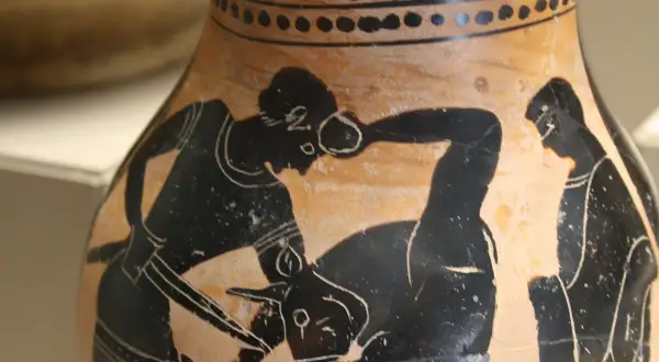 Vase antique représentant Thésée combattant le Minotaure. Un homme, qui est Thésée, lutte contre une créature mi-homme mi-taureau.