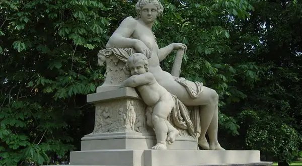 Statue de Hercule et Mégara, une femme assise et un enfant s'appuyant sur elle, dans un parc verdoyant.