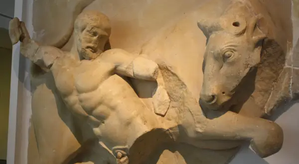 Sculpture antique d'Hercule luttant contre un taureau. Le héros, musclé, saisit l'animal par les cornes.