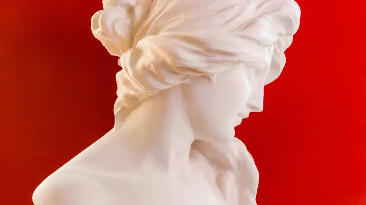 Buste en marbre blanc d'une femme aux cheveux tressés, évoquant la sérénité de Morphée, dieu des rêves.