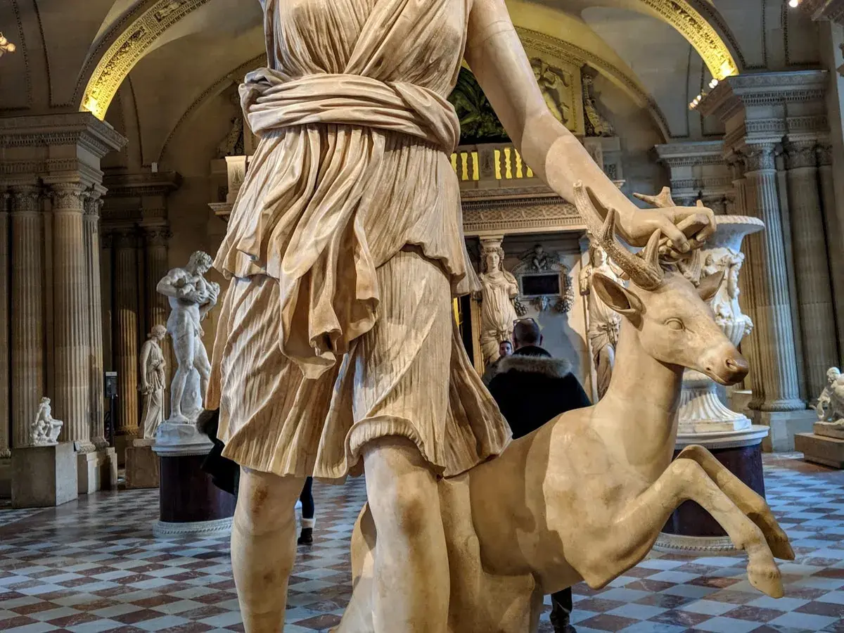 Statue d'Artémis caressant un cerf, un artémis animal emblématique de la déesse de la chasse, dans un musée.