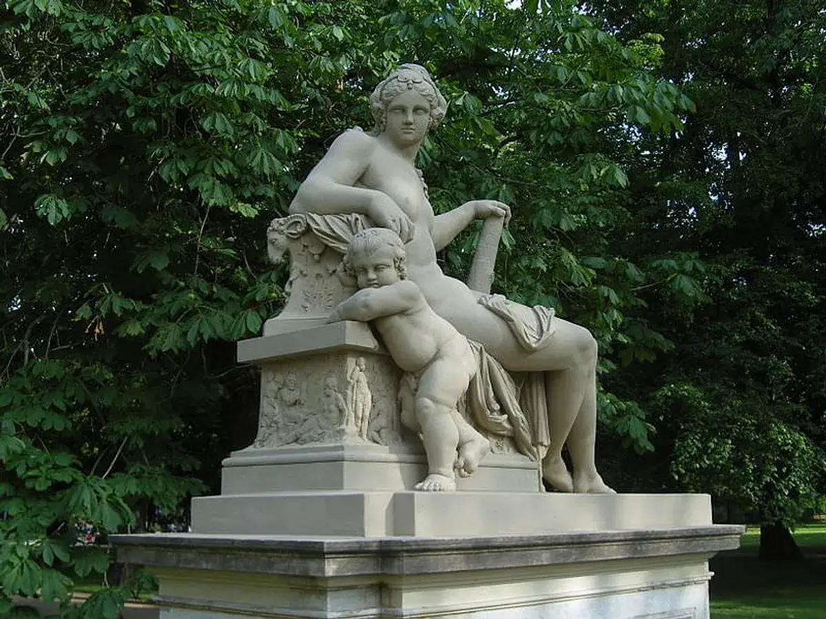 Statue de Hercule et Mégara, une femme assise et un enfant s'appuyant sur elle, dans un parc verdoyant.