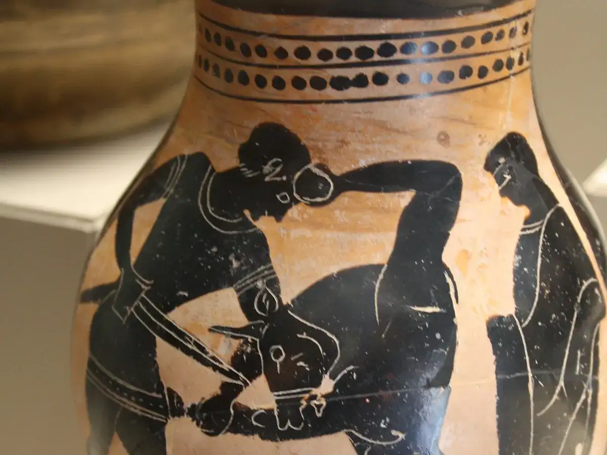 Vase antique représentant Thésée combattant le Minotaure. Un homme, qui est Thésée, lutte contre une créature mi-homme mi-taureau.