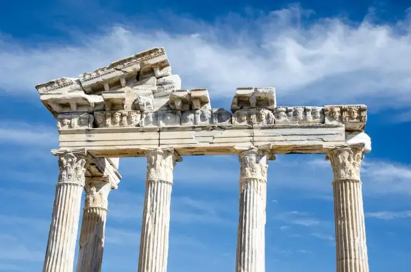 Ruines d'un temple grec, vestiges d'un dieu des arts grec, sous un ciel bleu et nuageux.
