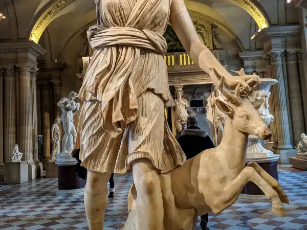 Statue d'Artémis caressant un cerf, un artémis animal emblématique de la déesse de la chasse, dans un musée.