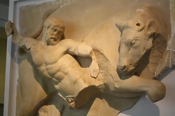 Sculpture antique d'Hercule luttant contre un taureau. Le héros, musclé, saisit l'animal par les cornes.